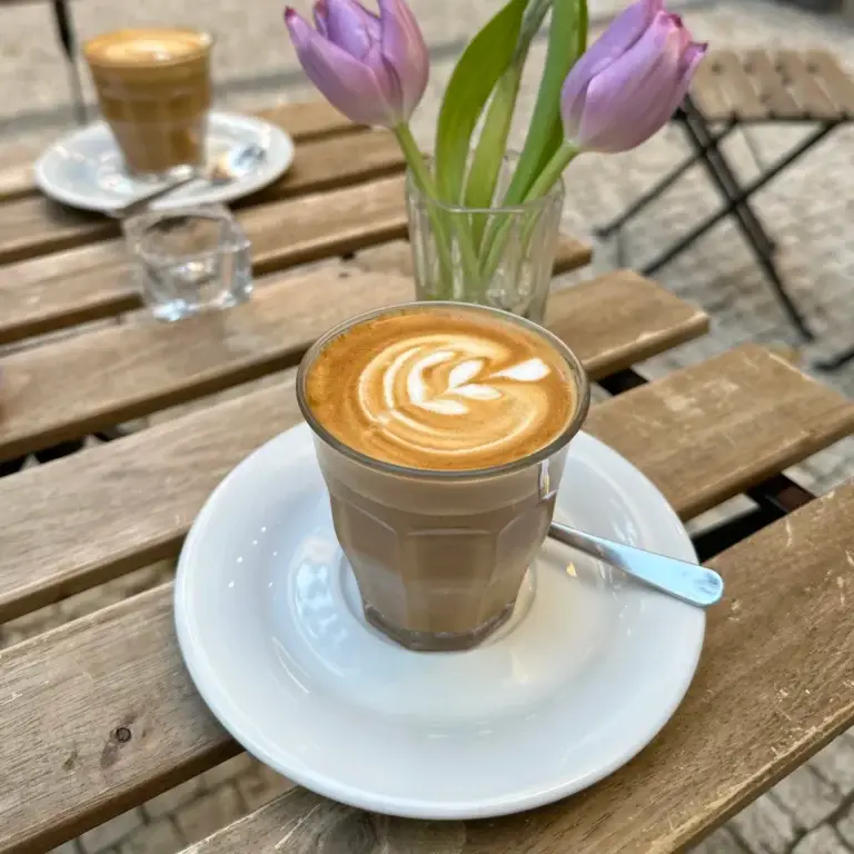 Latte with milk foam art served at an outdoor café table in Prague
